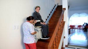 señora usando silla salvaescaleras tramos rectos instalada en centro para la tercera edad - Smart Motion S.A.S.